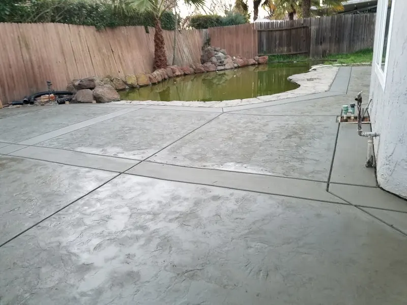 Concrete patio by a backyard pond by Brickhouse Masonry, Central Valley CA