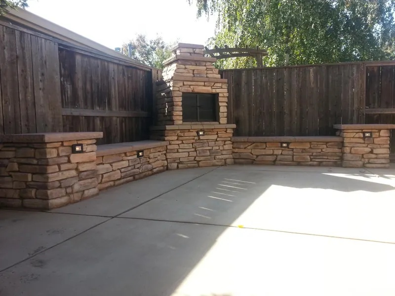 Outdoor fireplace with stone seat walls by Brickhouse Masonry, Central Valley CA